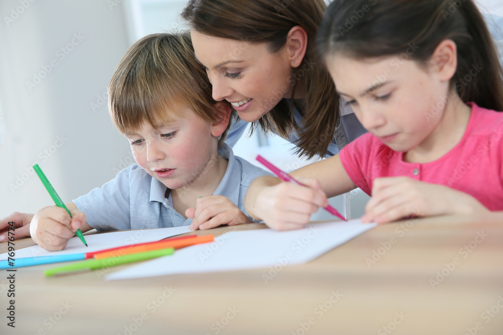 Mother watching kids at home while they are drawing Mother watching kids at home while they are drawing