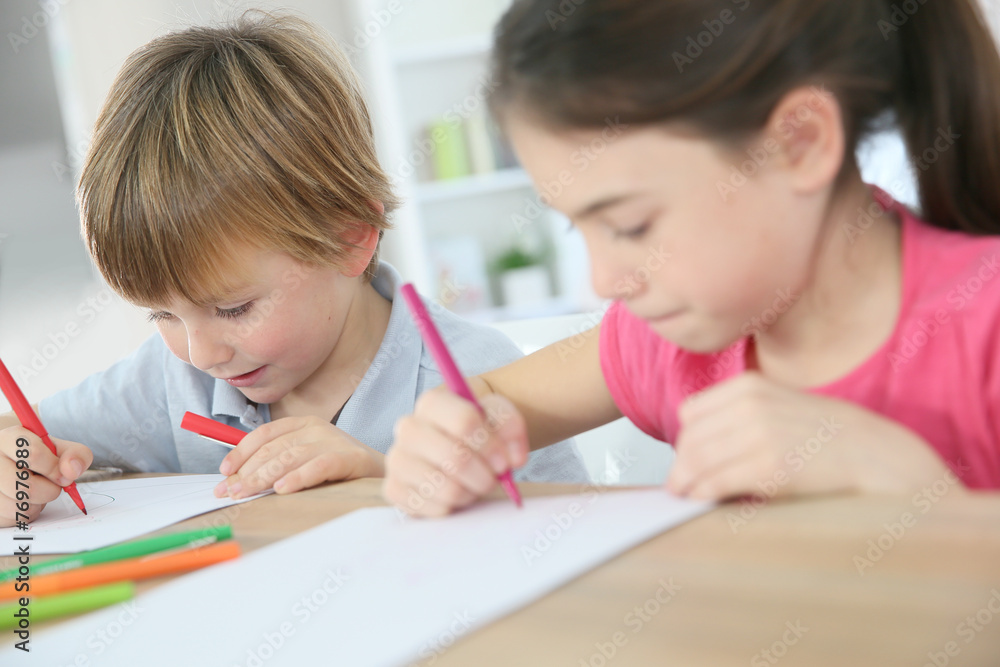 School kids sitting at table and writing on paper School kids sitting at table and writing on paper