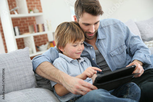 Father with little boy using digital tablet at home photo