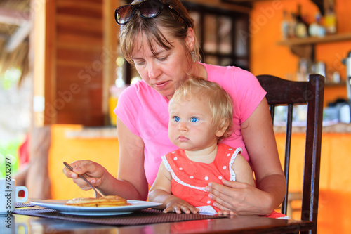 mother feeding infant daughter in cafe