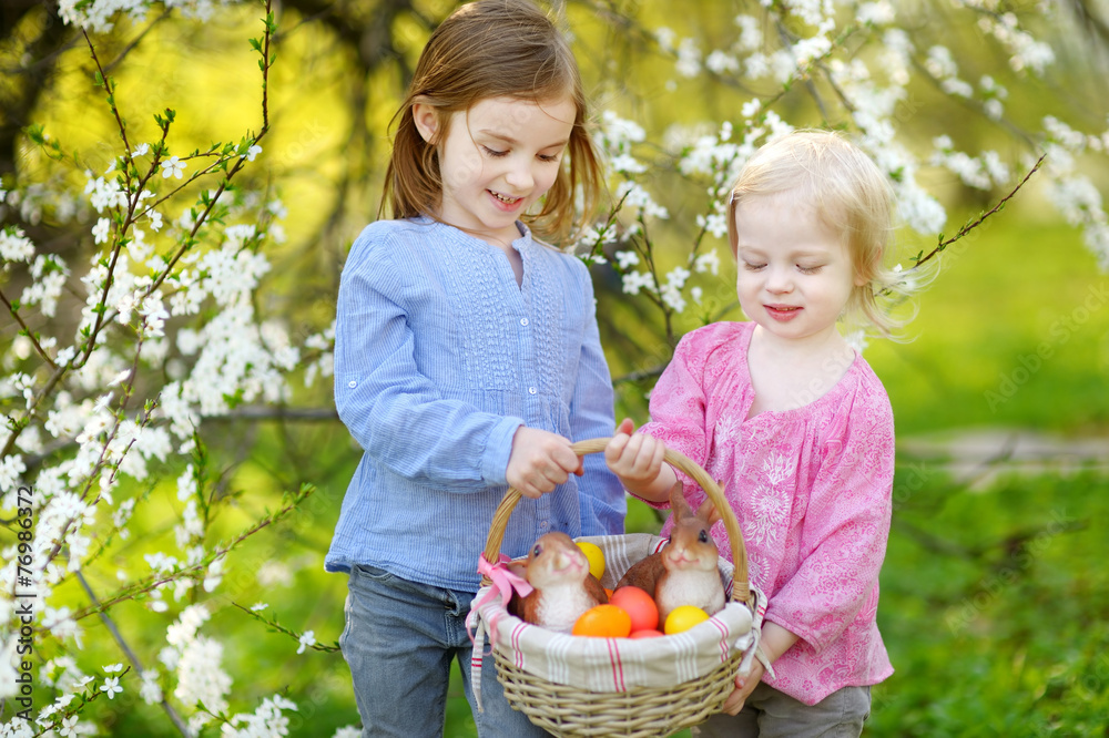 Two little girls holding a basket of Easter eggs Two little girls holding a basket of Easter eggs