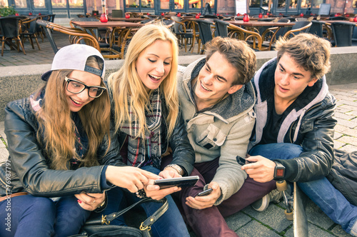 Young hipster friends having fun together with smartphones