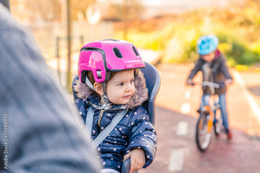 Lttle girl with helmet on head sitting in bike seat