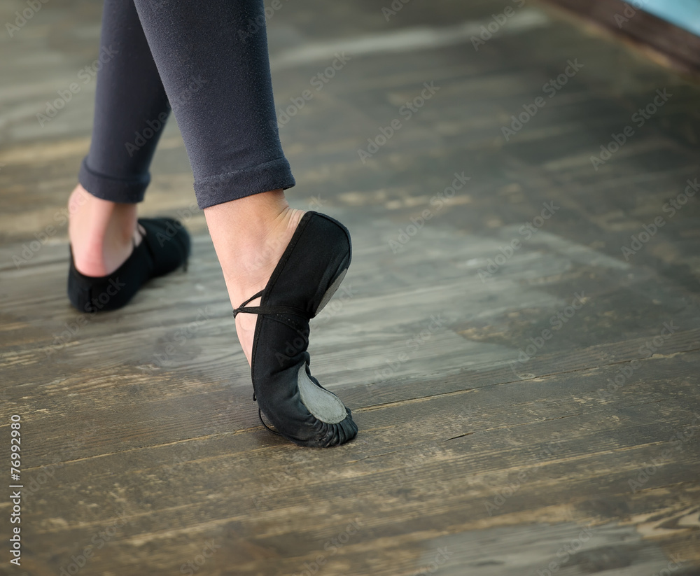 Close up view to ballerinas legs in pointes on wooden floor Close up view to ballerinas legs in pointes on wooden floor