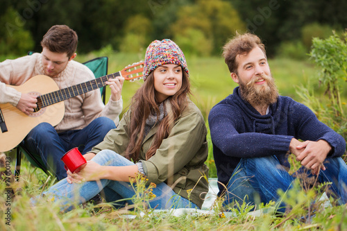 group of smiling friends with guitar outdoors © Syda Productions