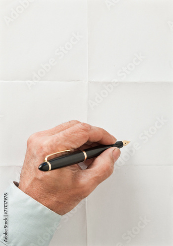 hand and pen write over sheet of paper