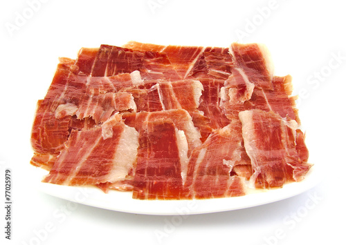 Serrano ham slices on a white dish. Jabugo. Spanish tapa.