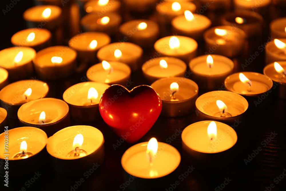 Burning candles with heart on dark background