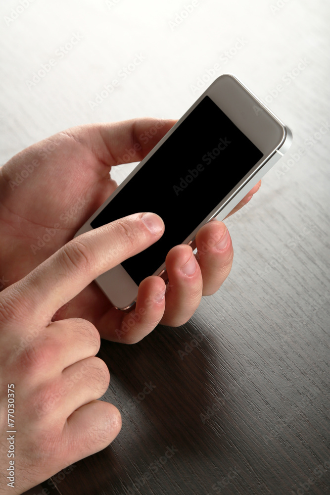 Hands holding smart mobile phone on wooden table background Hands holding smart mobile phone on wooden table background