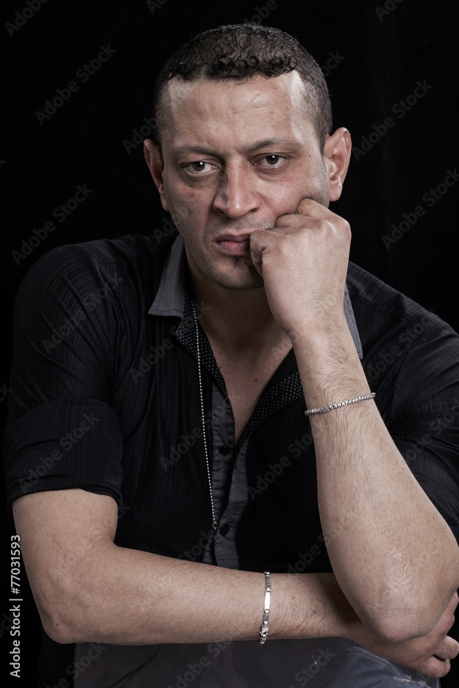 Frowning man portrait looking at camera on black background Frowning man portrait looking at camera on black background
