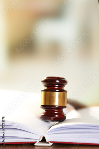 Wooden judges gavel lying on law book, close up photo