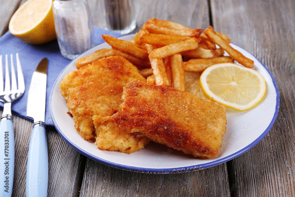 Breaded fried fish fillets and potatoes with with sliced lemon Breaded fried fish fillets and potatoes with with sliced lemon