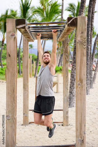 Fitness man on monkey bars fitness station gym photo