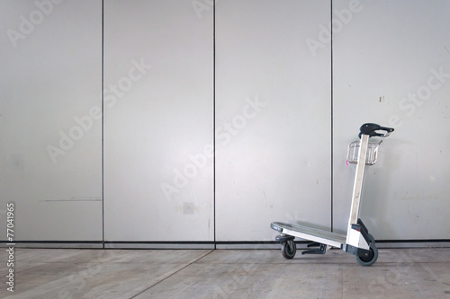 Airport luggage cart in front of wall.