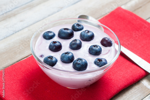 Yogurt with blueberries on red cloth, wooden background