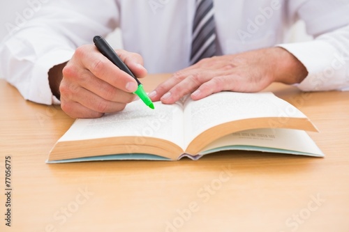 Casual businessman sitting at desk reading a book