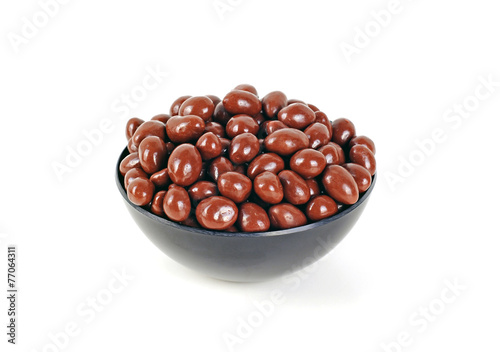 Peanuts covered by milk chocolate, on a black bowl