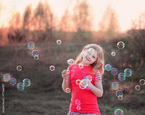 girl blowing soap bubbles outdoor at sunset