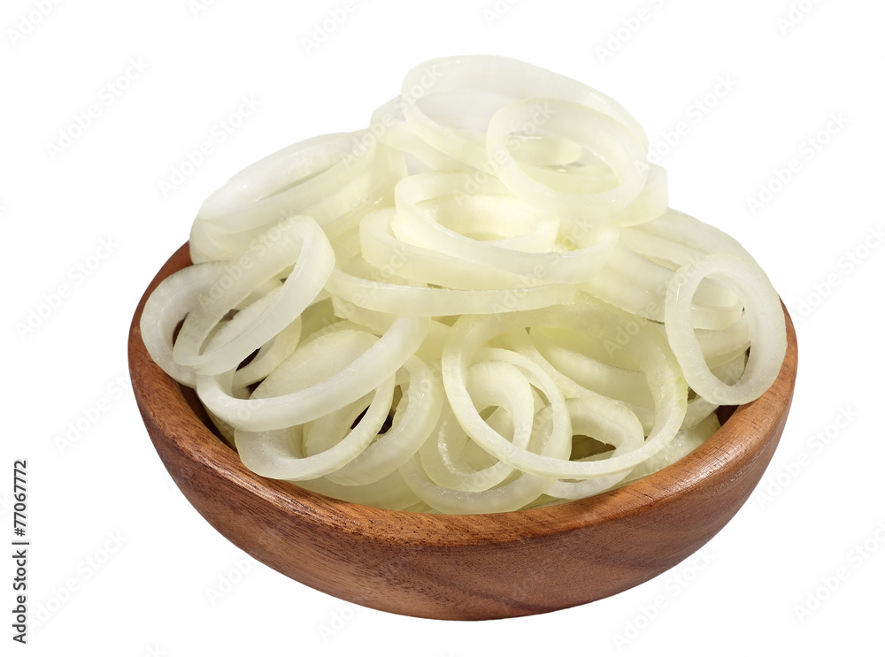 Onion slices in a wooden bowl on a white Onion slices in a wooden bowl on a white