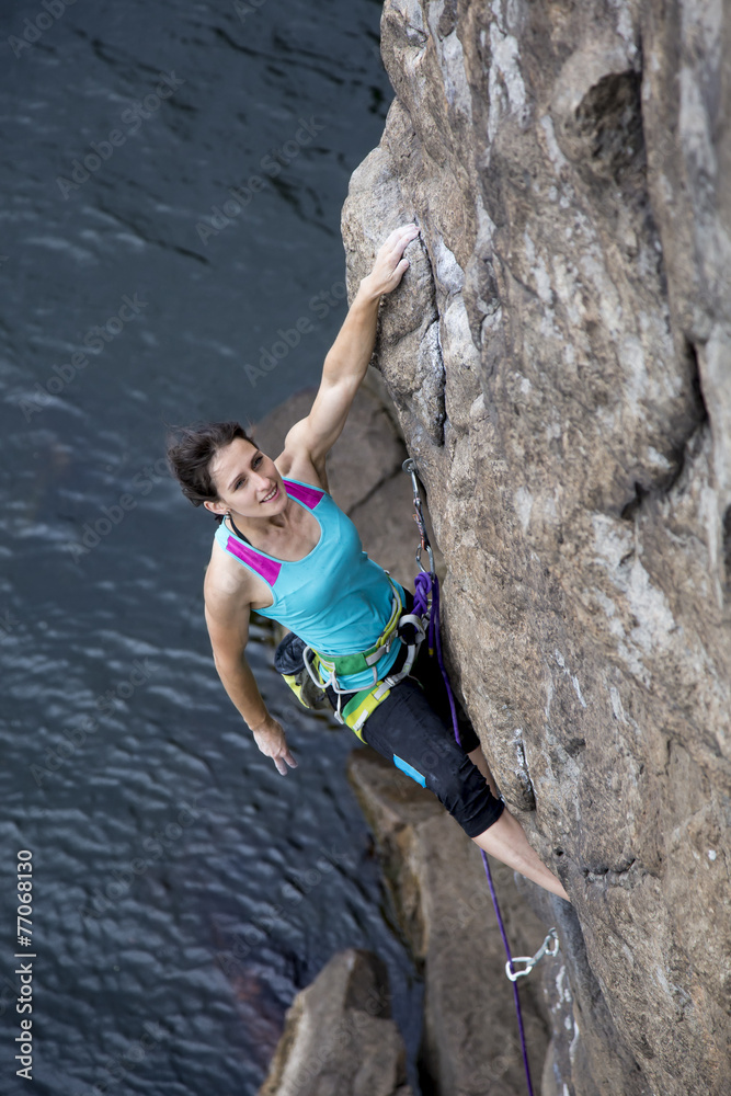 Female rock climber hanging over the sea
