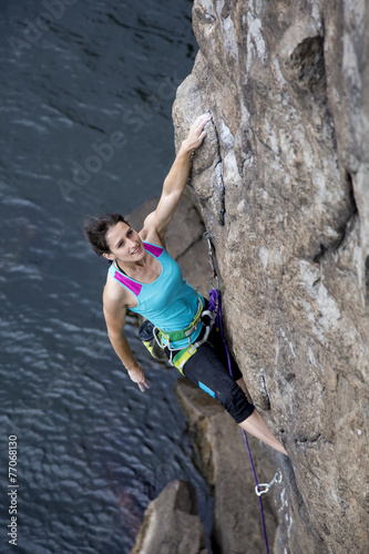 Female rock climber hanging over the sea