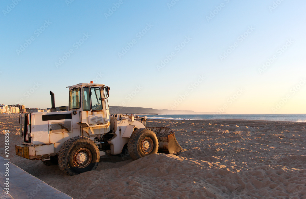 The tractor standing on the beach at sunset time The tractor standing on the beach at sunset time