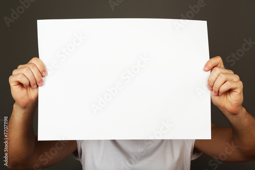 Blank sheet of paper in male hand on dark background © Africa Studio