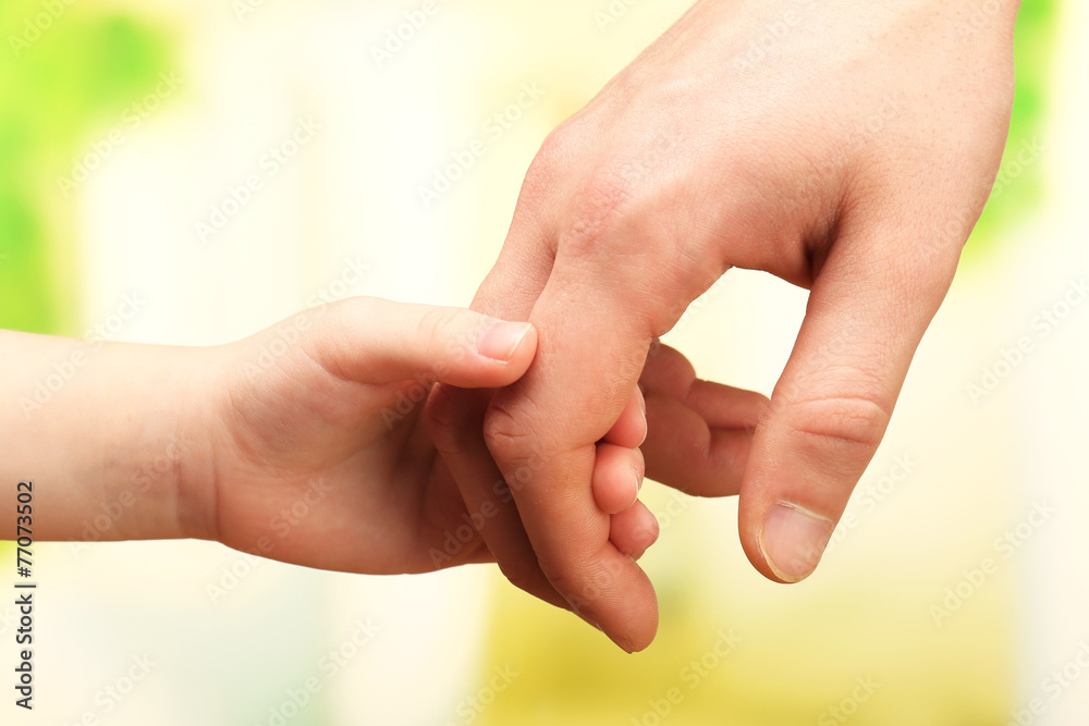 Child and father hands on bright background Child and father hands on bright background