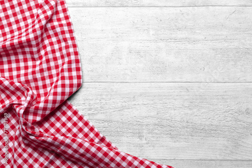 Red checkered tablecloth on white wooden table background photo