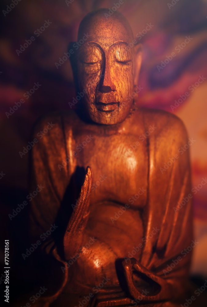 A wooden statue of meditating Buddha A wooden statue of meditating Buddha