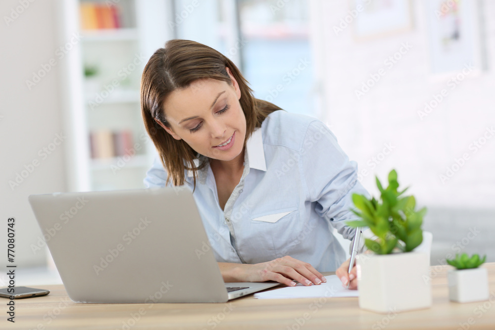 Woman in office working on laptop computer Woman in office working on laptop computer
