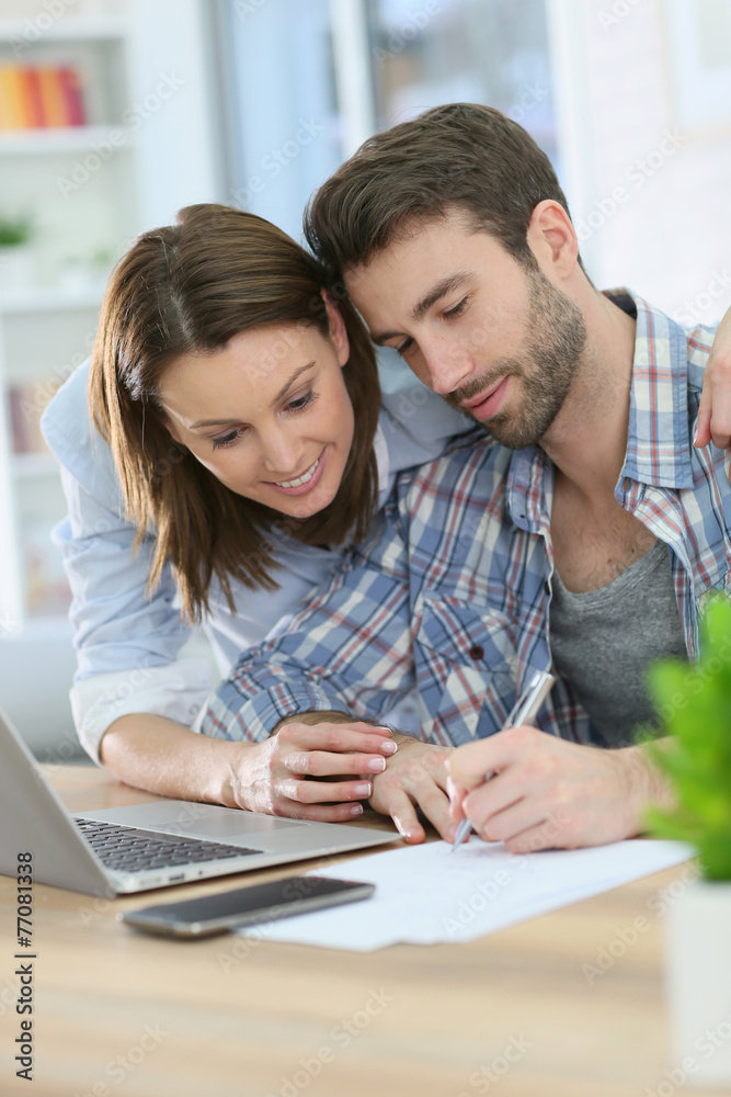 Couple using laptop computer and taking notes Couple using laptop computer and taking notes
