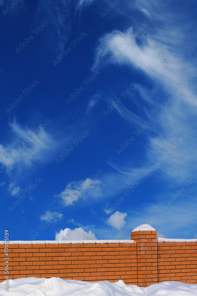 Brick fence on the background of blue sky in the winter time. Brick fence on the background of blue sky in the winter time.