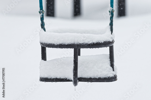 Snow covered swing during w...