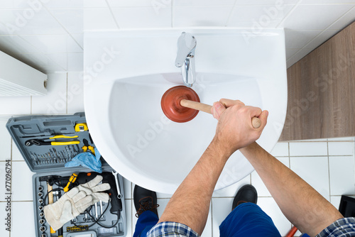 Male Plumber Using Plunger In Bathroom Sink photo