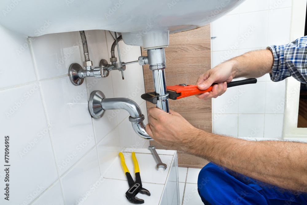 Male Plumber Fixing Sink In Bathroom Male Plumber Fixing Sink In Bathroom