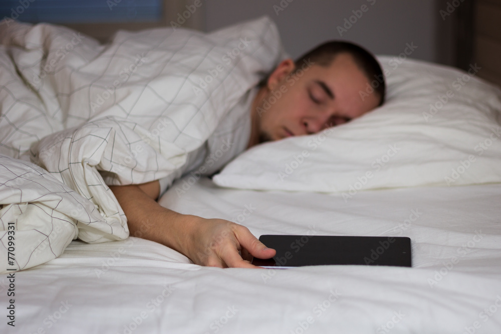 Man sleeping in bed and holding a tablet computer Man sleeping in bed and holding a tablet computer