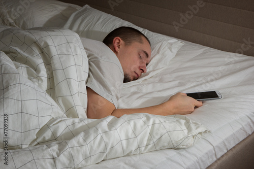 Man sleeping in bed and holding a mobile phone