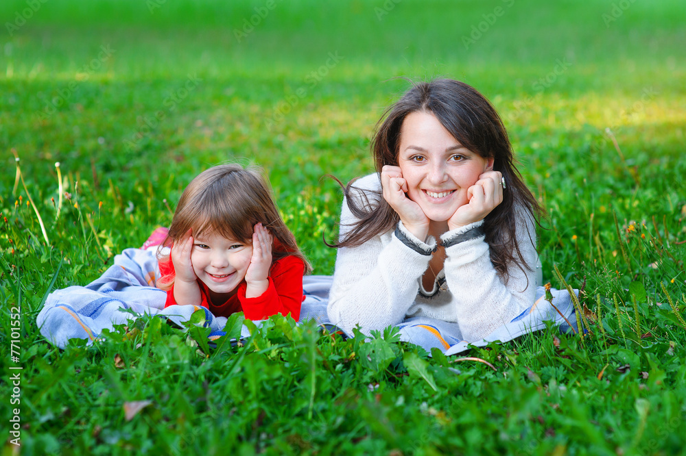 happy mother and daughter lie on the grass in the park happy mother and daughter lie on the grass in the park