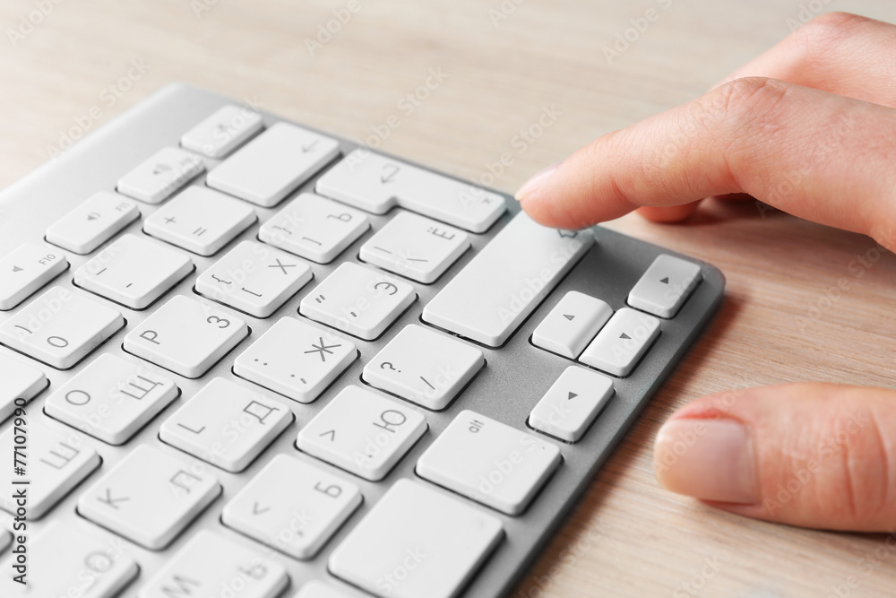 Female hand with keyboard on wooden desktop background Female hand with keyboard on wooden desktop background