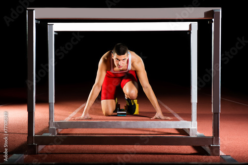 фотографія Athlete on the starting blocks with hurdles