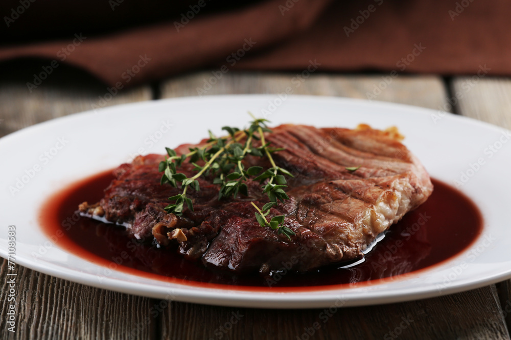 Grilled steak in wine sauce on plate on table close up