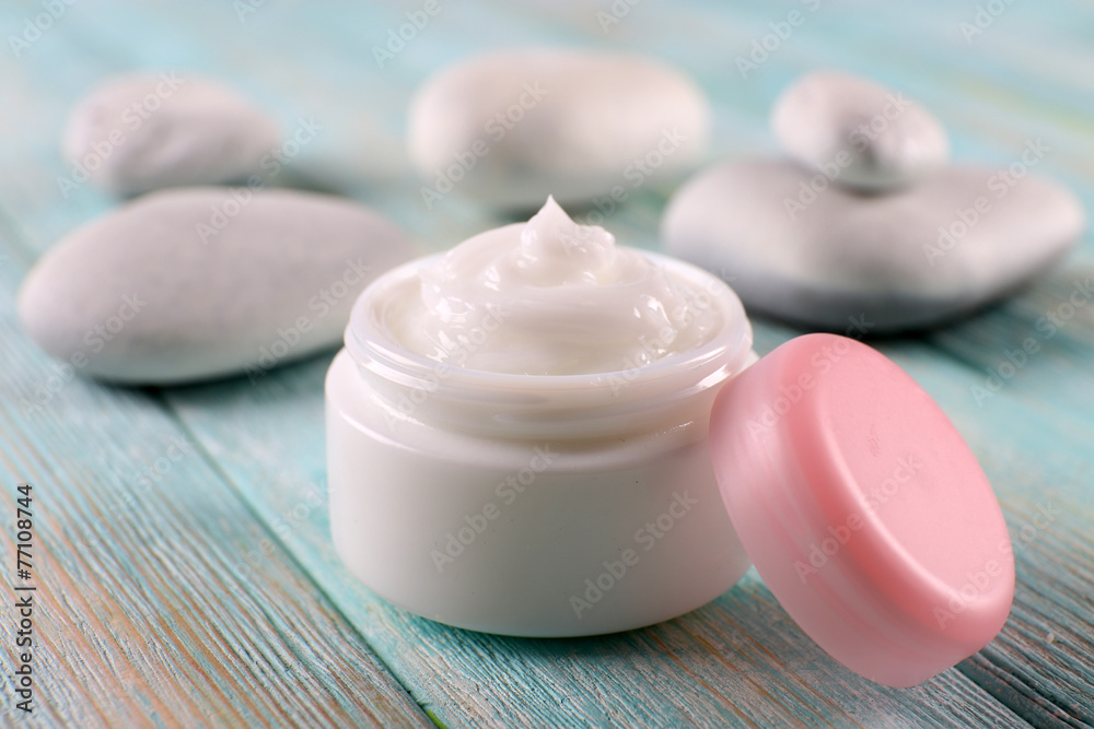 Cosmetic cream with spa stones on wooden background Cosmetic cream with spa stones on wooden background