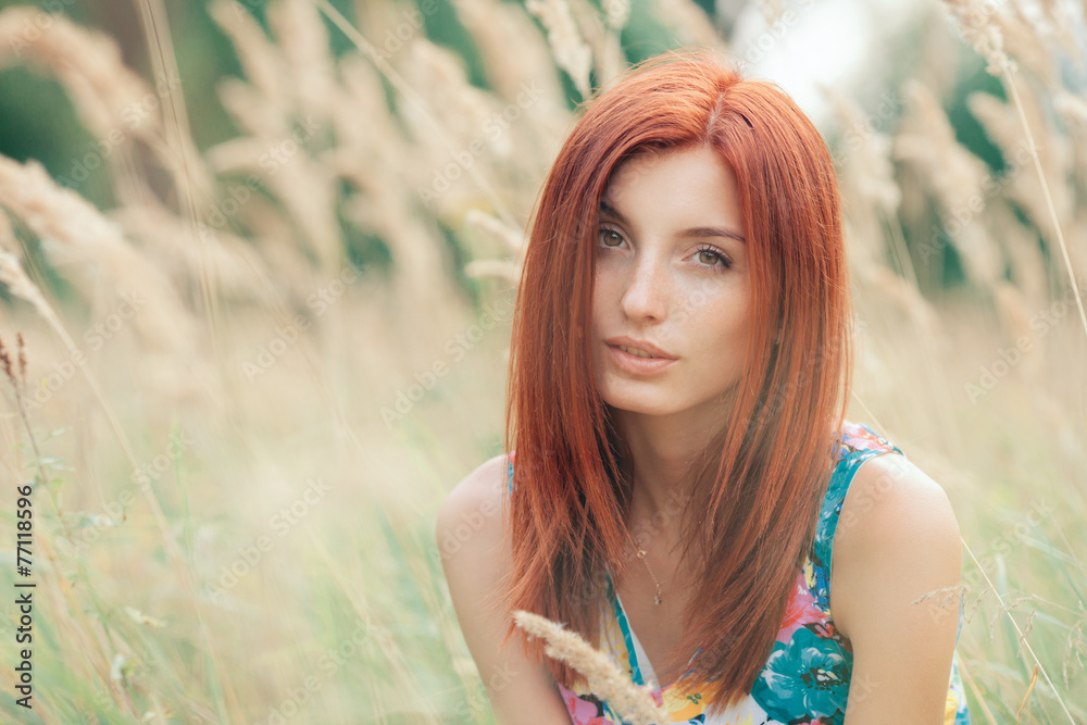 Closeup portrait of young  redhead woman posing at meadow