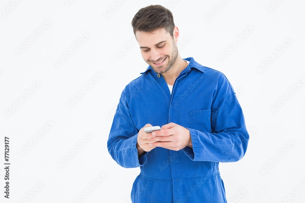 Male mechanic text messaging through mobile phone Male mechanic text messaging through mobile phone