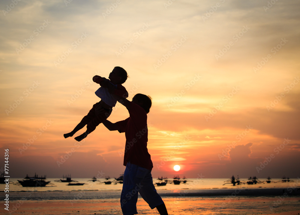 father and son silhouettes play at sunset