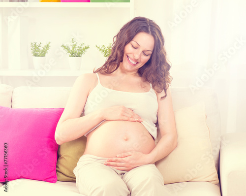 Pregnant happy woman sitting on a sofa and caressing her belly Free Download Pregnant happy woman sitting on a sofa and caressing her belly - GFXLoad