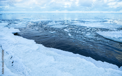 Winter coastal landscape with floating ice on still sea water