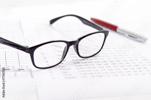 Business composition with glasses pen and financial statistics s