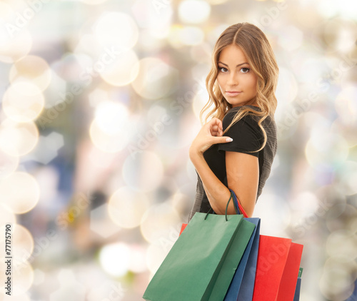 young happy woman with shopping bags over lights